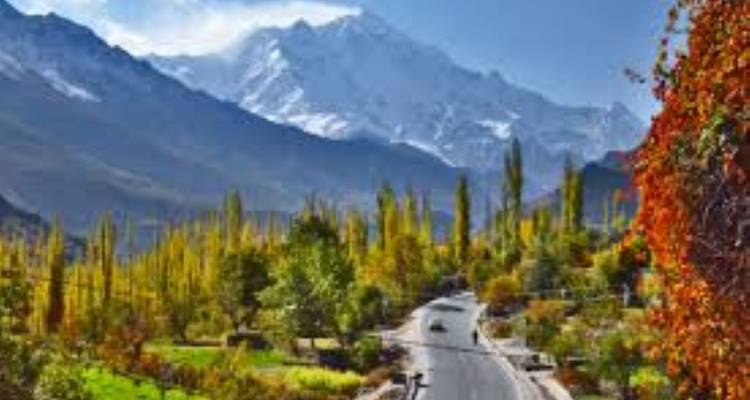 Pic enneigé dominant une vallée bordée de peupliers au début de l'automne