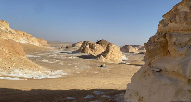 Formations rocheuses de craie et dunes de sable d'un autre monde dans le Désert Blanc sous un ciel dégagé.