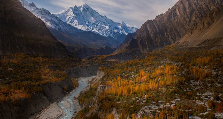 Río serpenteando a través del amplio valle de Hunza con follaje dorado de otoño y picos nevados imponentes