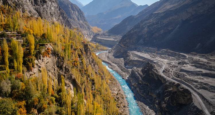 Río turquesa serpenteando a través de un desfiladero rocoso empinado bordeado de álamos dorados