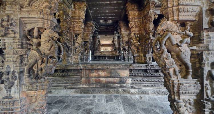 Innenraum mit kunstvoll geschnitzten Steinsäulen mit mythischen Figuren und Pferden.