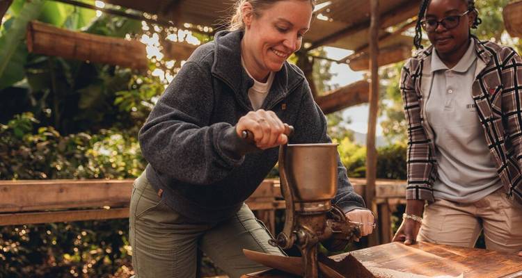 Des voyageurs moudent des grains de café avec un moulin à main traditionnel lors d'un atelier culturel.