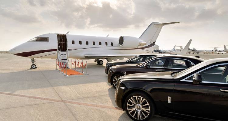 Privatjet auf dem Flughafenvorfeld mit luxuriösen schwarzen Limousinen, die daneben unter diesigem Himmel geparkt sind.