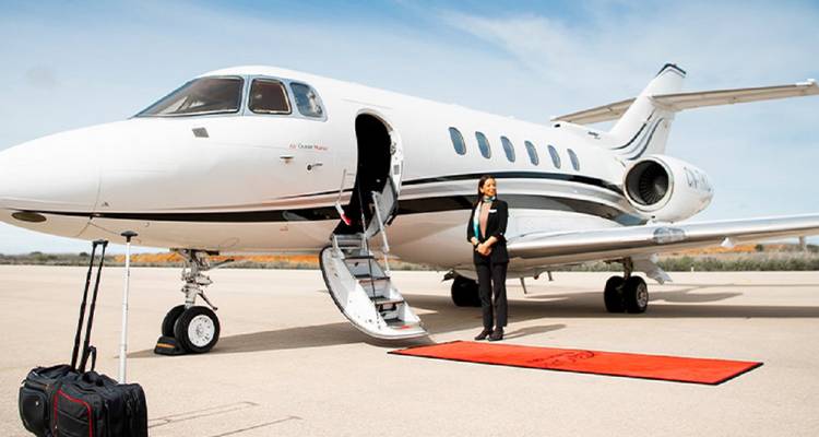 Zakenvliegtuig op het platform met stewardess die op een rode loper naast de open trap staat.