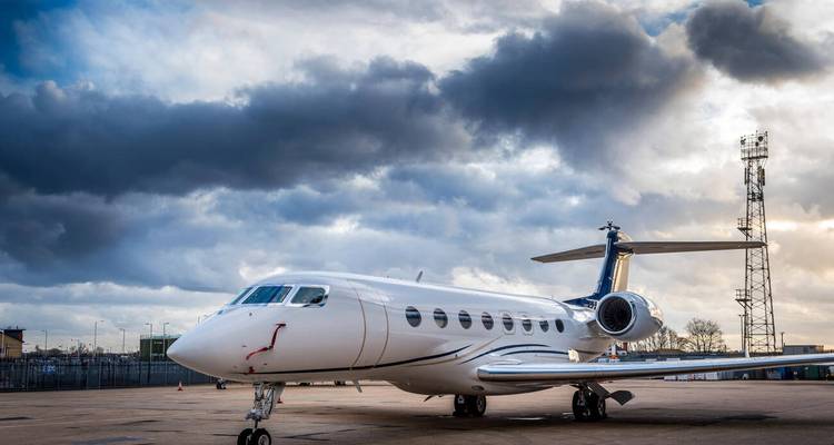 Wit Gulfstream straaljager gepositioneerd op landingsbaan onder dramatische onweerswolken.