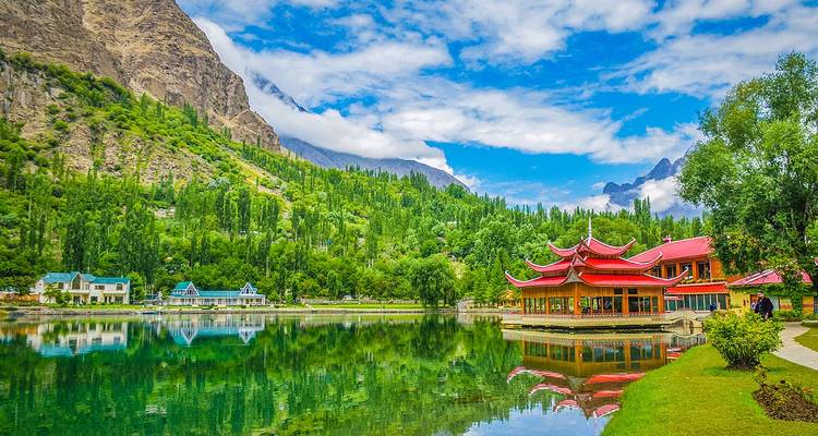 Lac pittoresque avec des bâtiments de station balnéaire de style pagode aux toits rouges adossés à des montagnes luxuriantes.