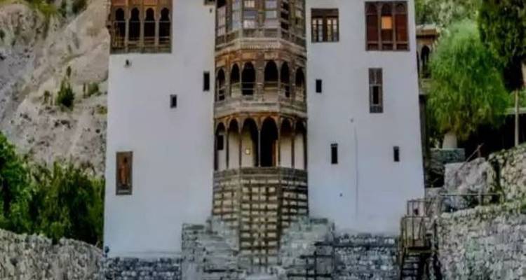 Fort ou palais historique au sommet d'une colline avec des balcons en bois, photographié d'en bas.