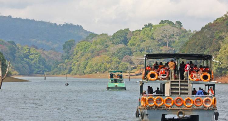 Bateaux d'excursion remplis de passagers naviguant le long d'un large lac forestier dans une réserve naturelle.