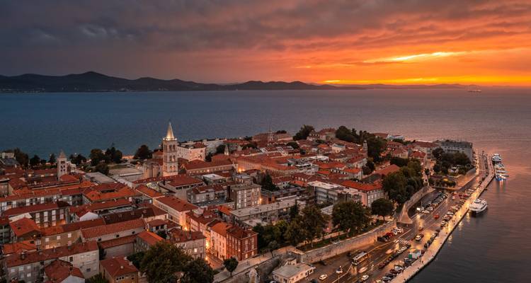 Luchtfoto van zonsondergang boven het schiereiland van Zadar met kerktoren en terracotta daken naast de Adriatische Zee.