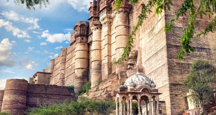 Indrukwekkende zandstenen bolwerken en sierlijke koepels van het Mehrangarh Fort die oprijzen tegen een blauwe hemel.