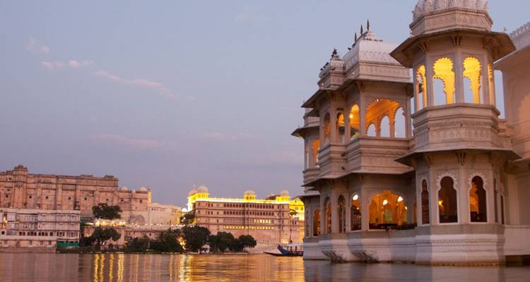 Romantisch schemerzicht van verlichte paleizen aan het meer die reflecteren op het kalme water in Udaipur.