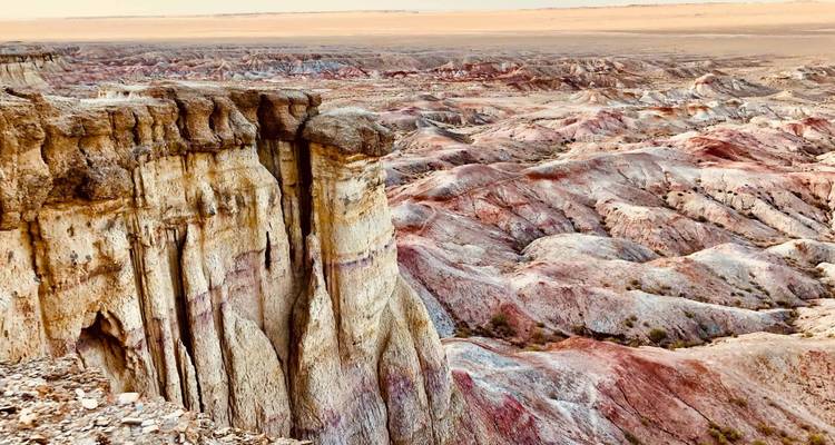 Falaises érodées aux rayures colorées et badlands s'étendant vers l'horizon d'un plateau désertique.