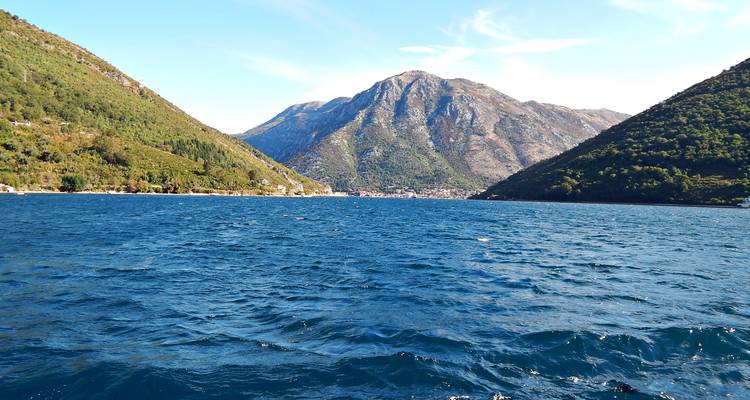 Deep blue waters of the Bay of Kotor surrounded by lush green mountains.