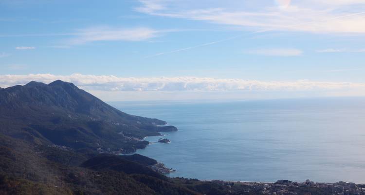 High vantage view of a mountainous coastline plunging into the Adriatic Sea under a clear blue sky.