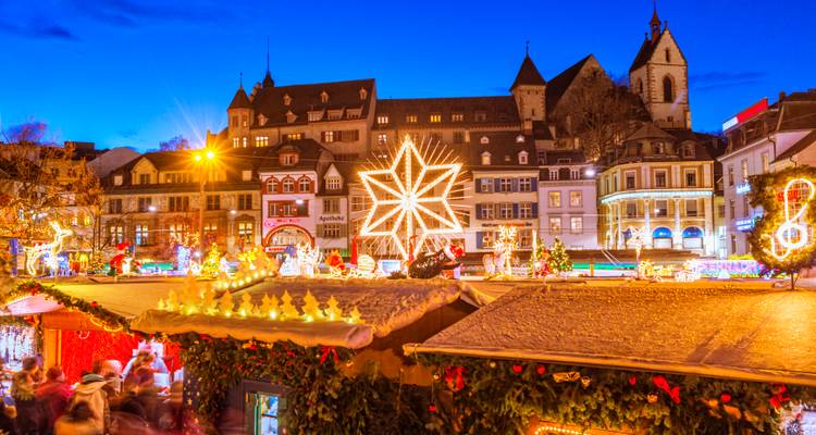 Marché de Noël coloré au crépuscule avec étoile géante illuminée et bâtiments allemands historiques en arrière-plan