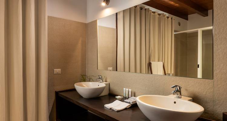 Modernes Hotelbadezimmer mit zwei freistehenden Waschbecken, großem Spiegel und neutralen Farbtönen.