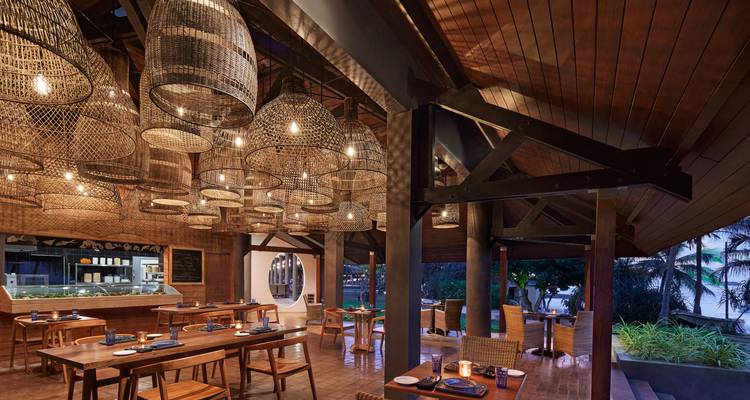Stilvolles Holzrestaurant-Interieur mit geflochtenen Korbleuchten und warmer Atmosphäre.