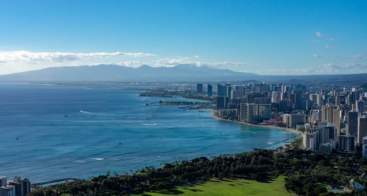 Uitgebreid uitzicht over Waikiki's wolkenkrabbers en turquoise kustlijn gezien vanaf een verhoogd uitkijkpunt.