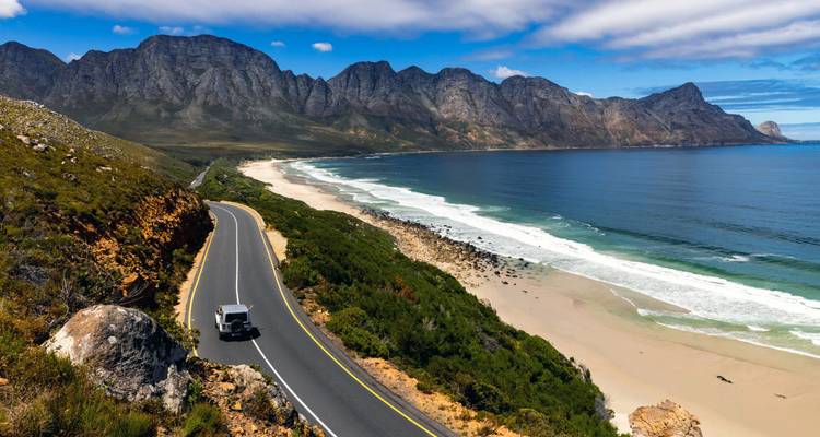 L'autoroute côtière serpente le long de montagnes spectaculaires et d'une mer turquoise sous des nuages lumineux.