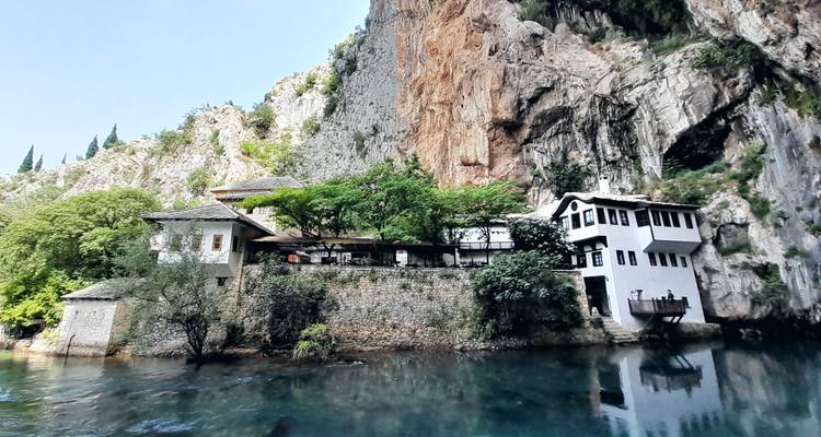 The white Ottoman teahouse monastery of Blagaj rests at the base of a sheer cliff above the emerald Buna spring.