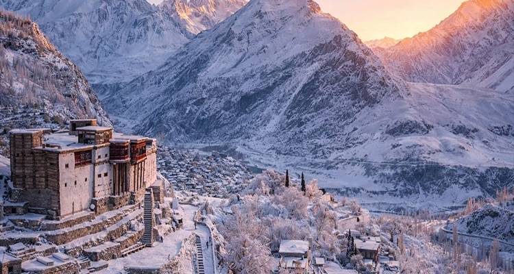 Valle de Hunza cubierto de nieve al amanecer con fuerte antiguo y picos montañosos resplandecientes