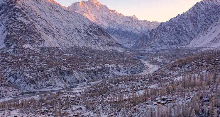 Amplio valle invernal con luz rosada matutina iluminando las cumbres distantes
