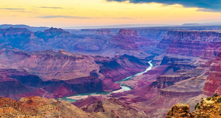Vastes couches colorées du Grand Canyon avec le fleuve Colorado serpentant au coucher du soleil