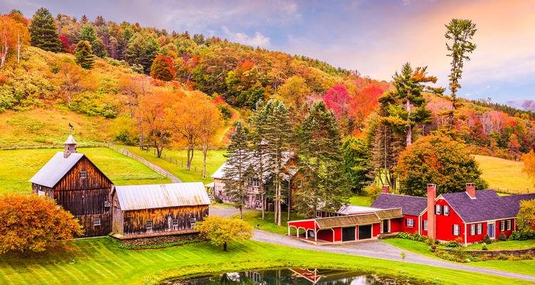 Idyllisches Gehöft in Vermont mit roten und hölzernen Scheunen inmitten sanfter Herbsthügel.