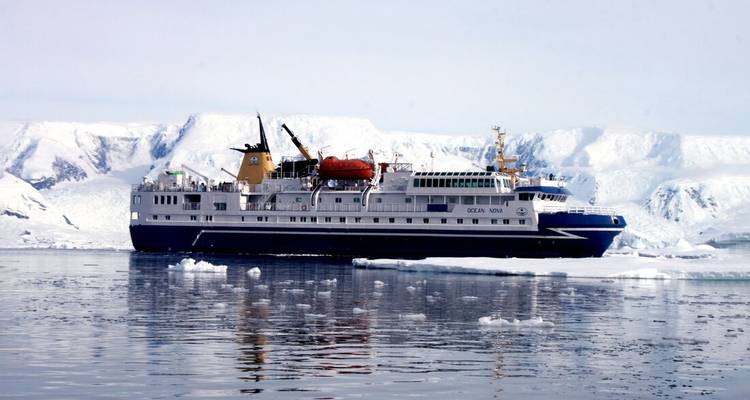 Navire d'expédition Ocean Nova naviguant dans les eaux glacées de l'Antarctique avec des glaciers en arrière-plan.