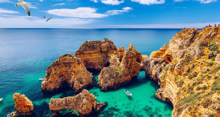 Aguas esmeralda y espectaculares arcos rocosos de la costa del Algarve vistos bajo gaviotas que vuelan en lo alto.