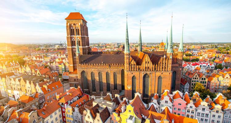 Vue aérienne ensoleillée de l'église Sainte-Marie dominant les toits colorés de la vieille ville de Gdansk.