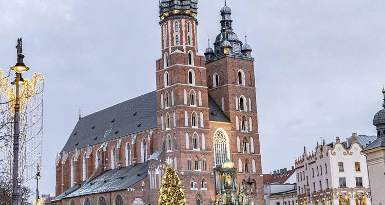 La Basílica Gótica de Santa María se alza sobre la nevada plaza del mercado de Cracovia decorada para Navidad.
