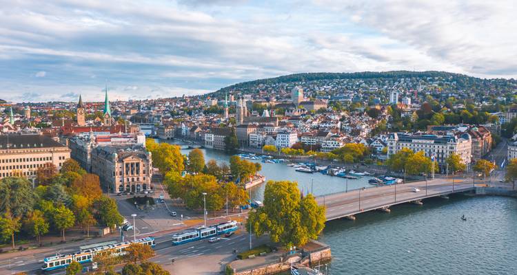Vue aérienne de Zurich avec son lac, ses ponts et ses quais bordés d'arbres sous un ciel nuageux