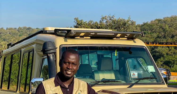 Guide de safari se tient fièrement à côté d'un véhicule 4x4 au parc national de Murchison Falls.