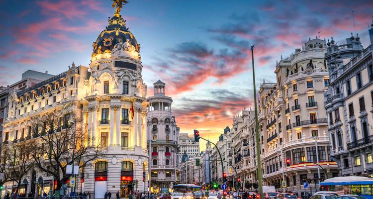 Metropolis-Gebäude und kunstvolle Fassaden entlang Madrids Gran Vía erstrahlen unter einem dramatischen Sonnenuntergangshimmel