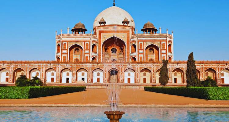 Vooraanzicht van Humayun's Tombe met een centrale fontein die water spuit onder een blauwe hemel