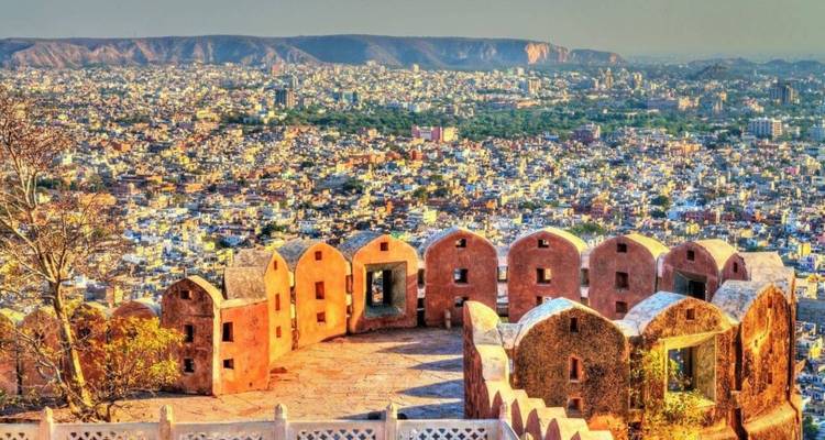Panoramisch uitzicht op de stad Jaipur vanaf Nahargarh Fort met door de zon beschenen vestingmuren op de voorgrond