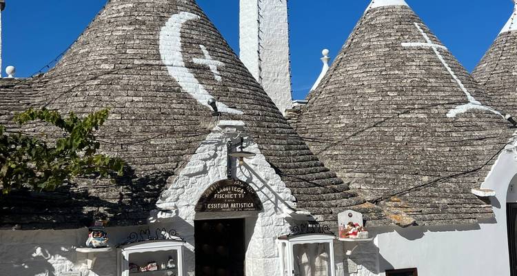 Maisons trulli coniques traditionnelles avec des symboles blanchis à la chaux sous un ciel bleu profond