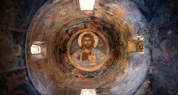 Une fresque complexe du Christ de style byzantin orne le plafond voûté d'une église orthodoxe.