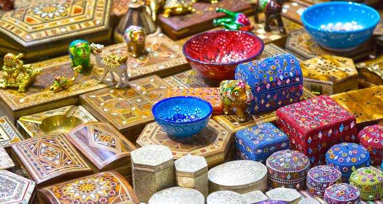 Bunt gefärbte Schalen, Schachteln und Figuren füllen einen geschäftigen omanischen Souk-Stand.