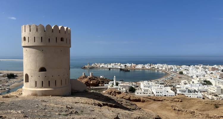 Runder Wachturm krönt einen felsigen Hügel mit Blick auf die weiß getünchte Küstenstadt Sur.