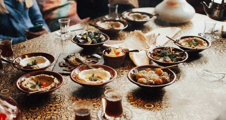 Auswahl an traditionellen jordanischen Mezze und Tee, angerichtet auf einem kunstvoll verzierten Esstisch.