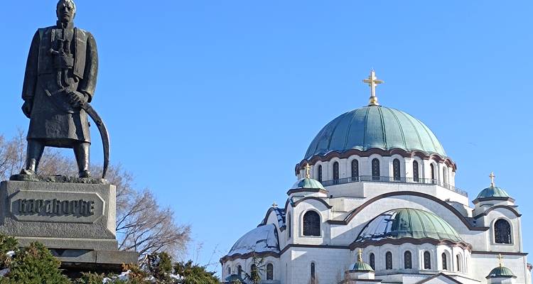 Standbeeld van Karadjordje naast de koepelvormige Sveti Sava Tempel onder een heldere blauwe hemel.