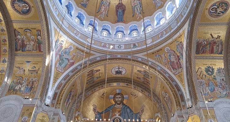 Ingewikkelde gouden mozaïeken en een Christus Pantocrator-icoon sieren de hoge binnenkoepel van de Sint-Sava Tempel.