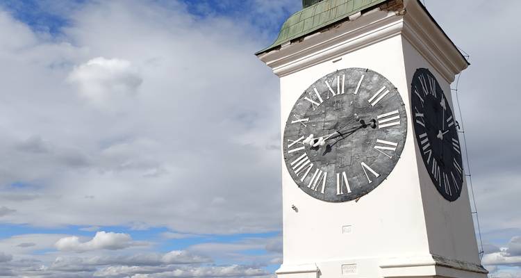 Iconische klokkentoren van de Petrovaradin vesting tegen een gedeeltelijk bewolkte hemel.