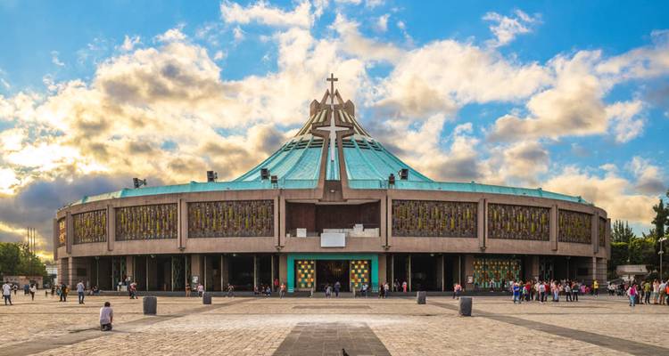 Vue de face de la Basilique circulaire moderne de Notre-Dame de Guadalupe sous des nuages dramatiques.