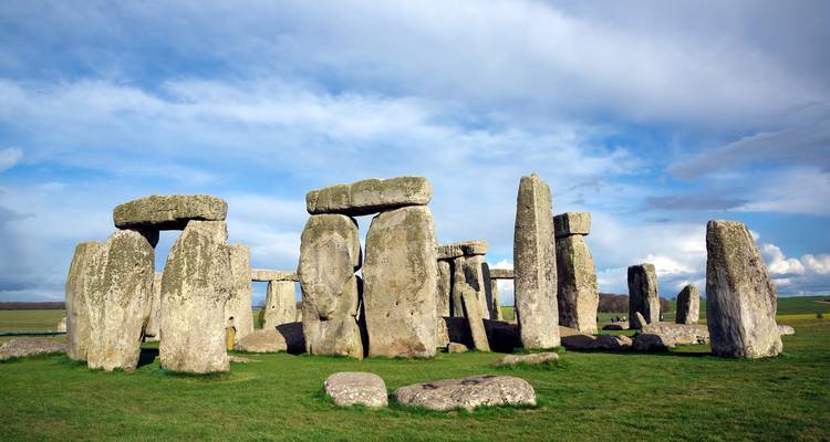 Icónico círculo de piedra prehistórico de Stonehenge erguido sobre hierba verde bajo un cielo dramático.