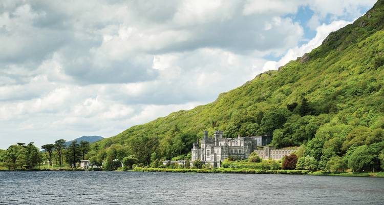 La Abadía de Kylemore neogótica y los jardines amurallados victorianos enclavados al pie de una montaña verde boscosa junto a un lago sereno.
