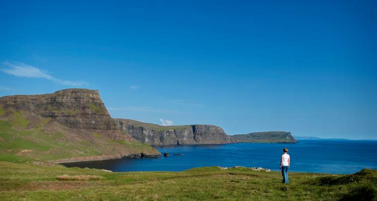 Viajero solitario contempla los espectaculares acantilados marinos irlandeses y el Atlántico azul bajo un cielo despejado