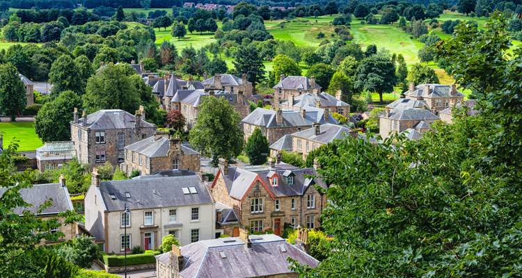 Charmant village écossais de maisons de pierre niché parmi les arbres avec un terrain de golf en arrière-plan